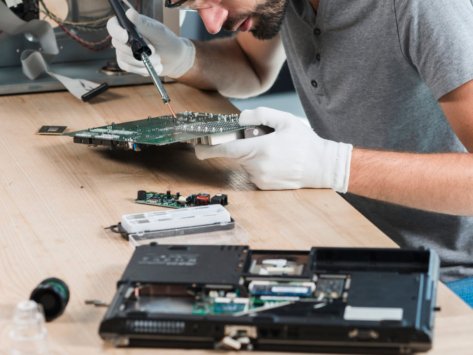 male-technician-repairing-computer-motherboard-wooden-desk