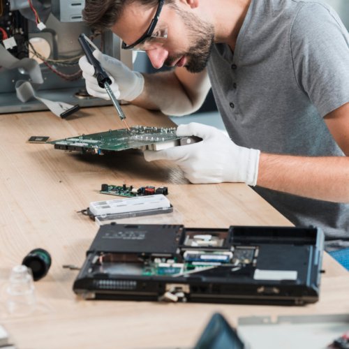 male-technician-repairing-computer-motherboard-wooden-desk